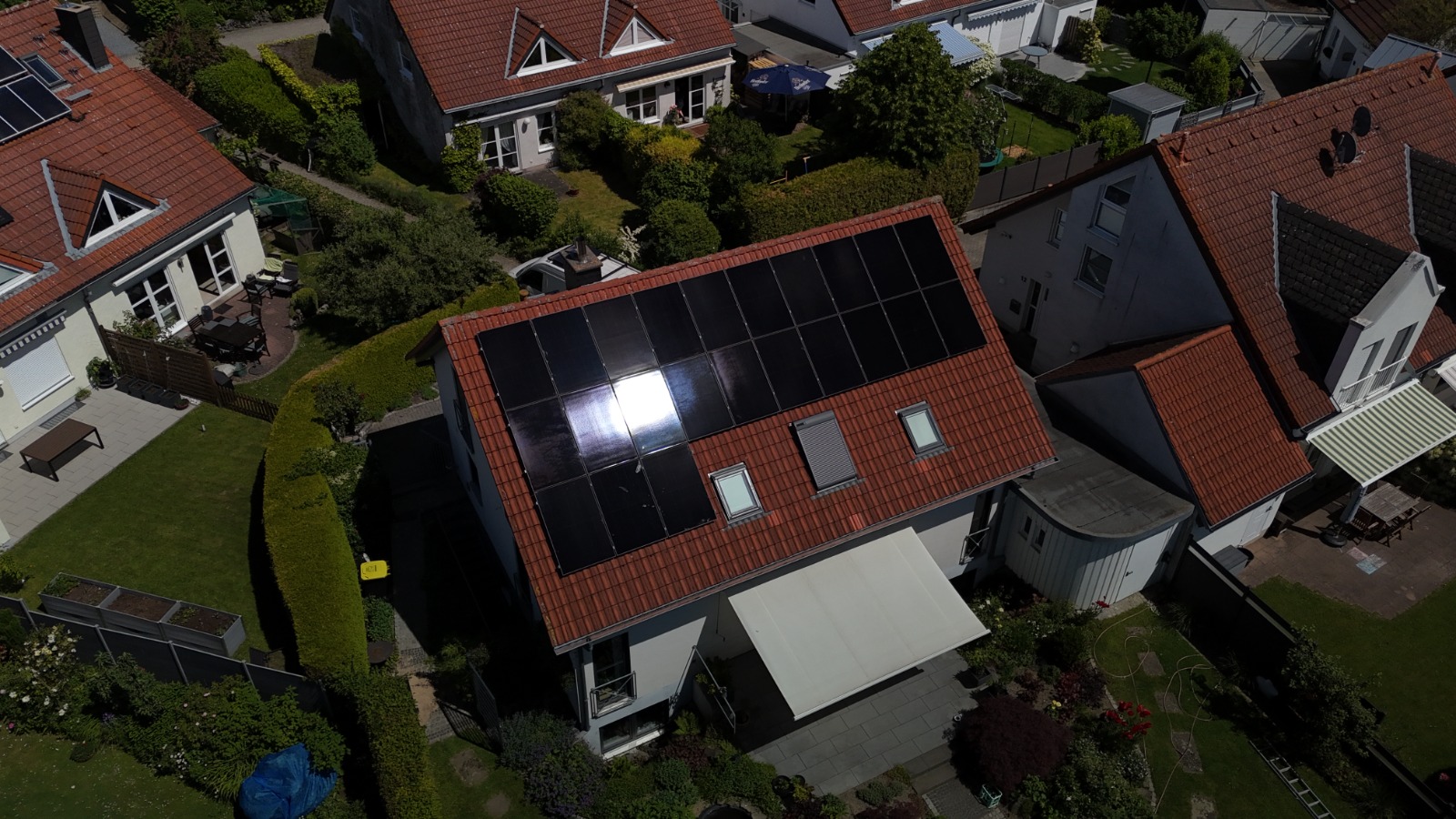 Luftaufnahme einer Photovoltaikanlage auf dem roten Ziegeldach eines Einfamilienhauses