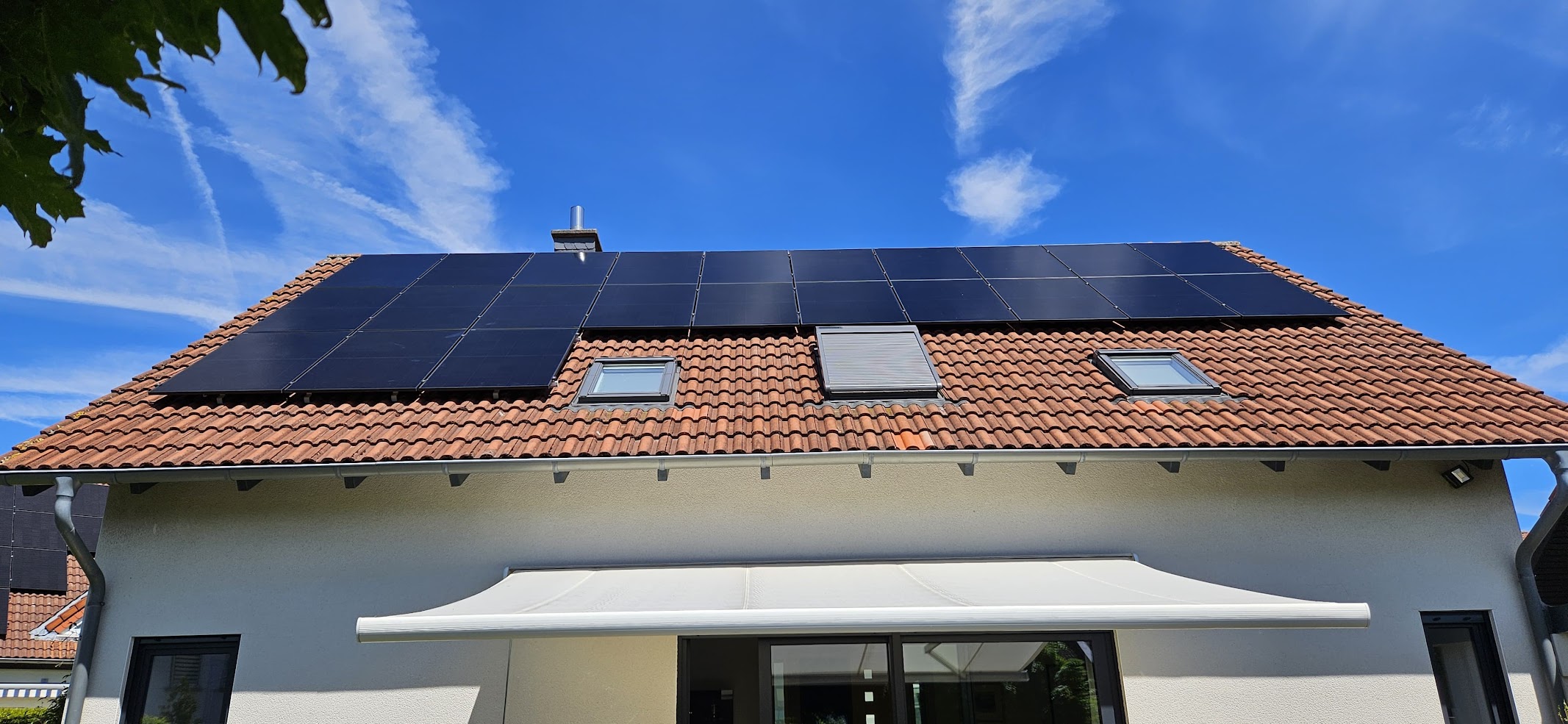 Fertig montierte Photovoltaikanlage auf einem roten Ziegeldach bei strahlendem Sonnenschein