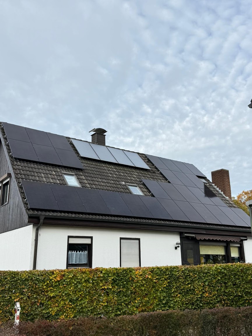 Vollbelegte Photovoltaikanlage mit schwarzen Modulen auf dem Satteldach eines weißen Einfamilienhauses