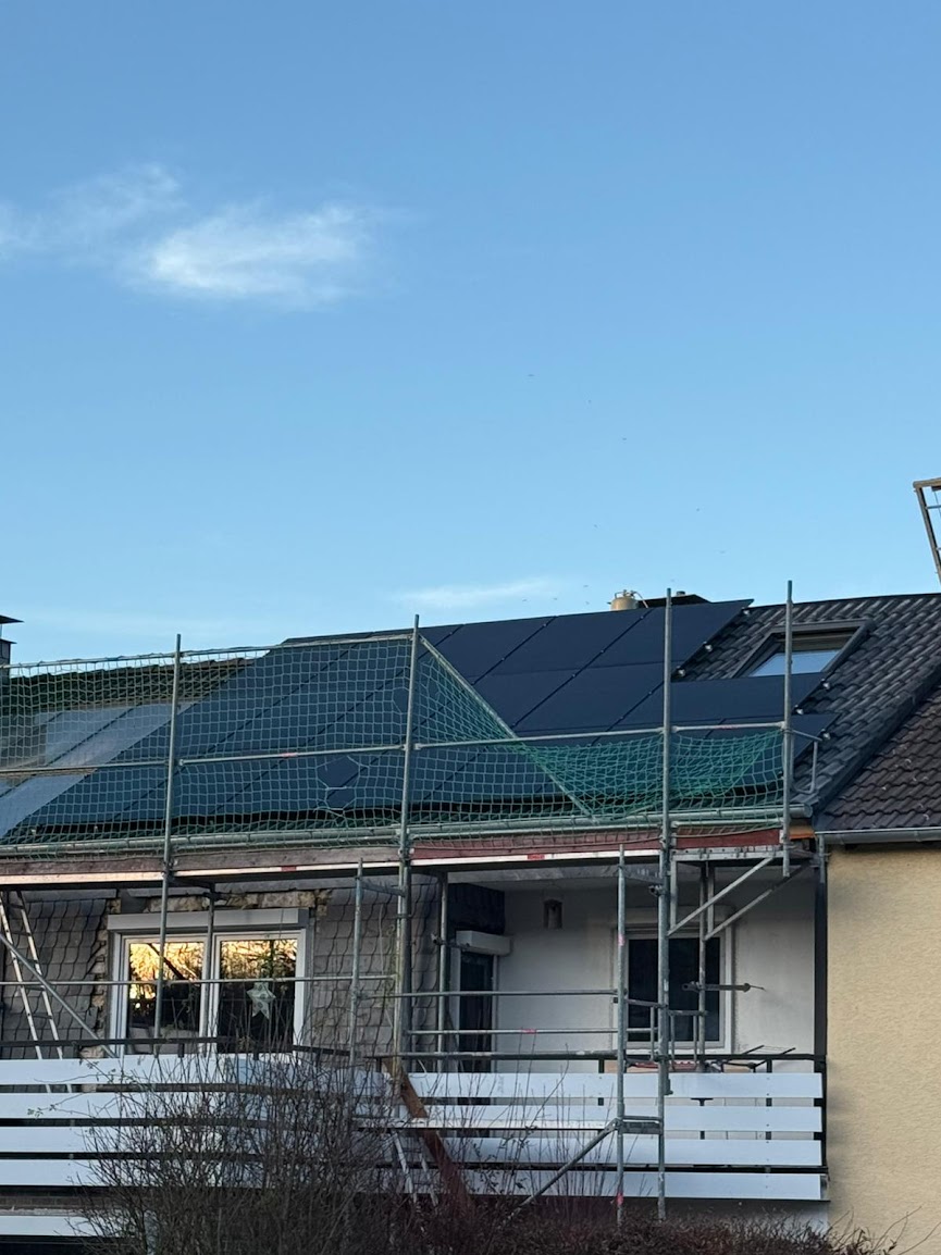 Photovoltaik-Montage mit Gerüst und grünem Sicherheitsnetz – Arbeitssicherheit auf der Baustelle